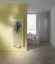 Vertikaler Heizkörper in Weiß mit Längsrippen, montiert an einer gelben Wand, im modernen Badezimmer mit Dusche und Badewanne im Hintergrund. Kermi-Design.